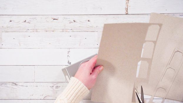 Flat lay. Step by step. Cutting out gift tags from brown paper with a paper punch.