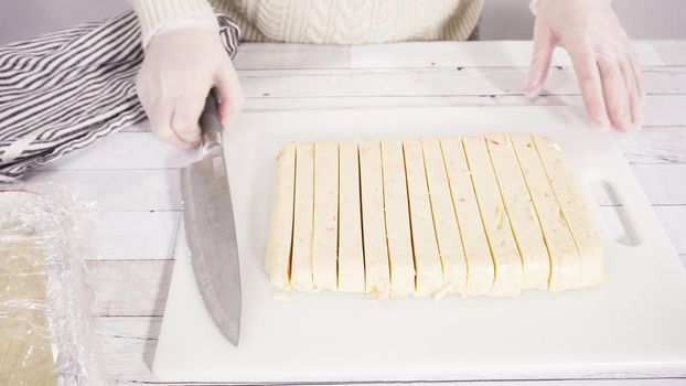 Step by step. Cutting homemade candy cane fudge on a white cutting board.