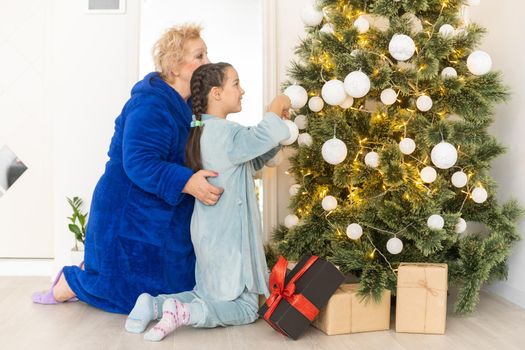 Grandmother and granddaughter decorating a Christmas tree