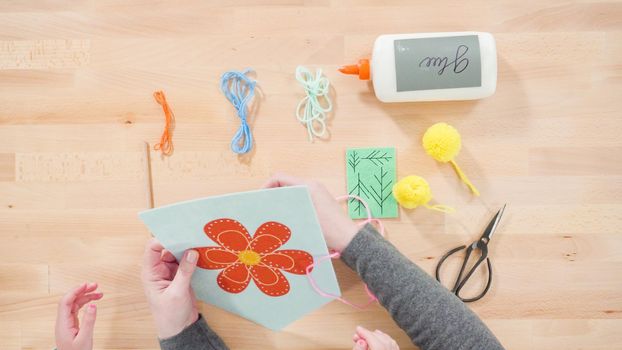 Little girl learning how to sew with her mother at the craft table.