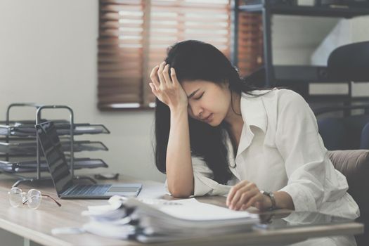 Stressed asian businesswoman with paperwork in the office. burnout syndrome or deadline project concept.