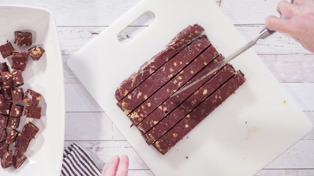 Flat lay. Step by step. Cutting homemade macadamia fudge on a white cutting board.