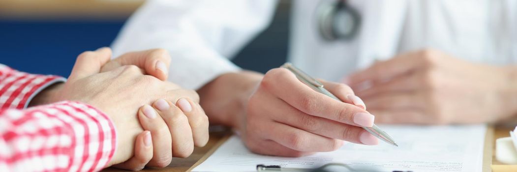 Close-up of patient on appointment explain problem to medical worker in clinic. Doctor write complaints on paper. Healthcare, medicine, diagnostic concept