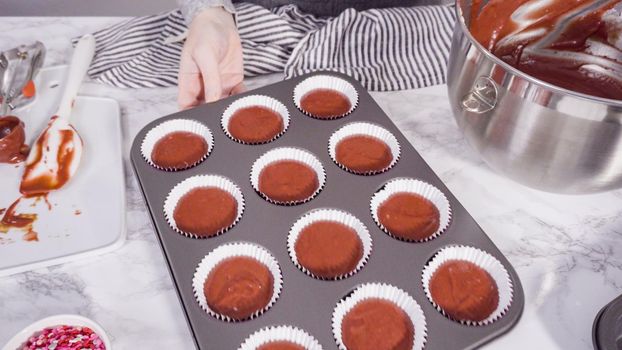 Step by step. Scooping cupcake batter into foil cupcake cups to bake red velvet cupcakes.