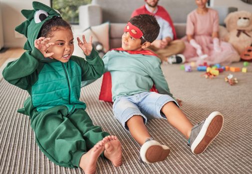 Family, halloween and children playing in costume on a floor in a living room, having fun and being creative. Superhero, dinosaur and creative kids bonding in character, excited and happy together.