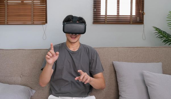 young asian man touching the air during the VR experience.