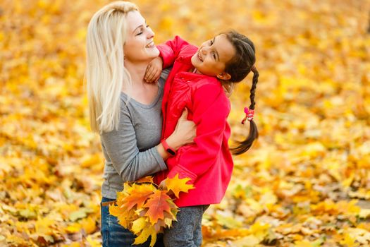 mother and daughter in the city park in autumn having fun time