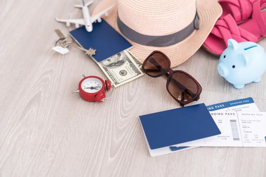 A piggy bank with dollar bills in a travel setting. In the composition of the image: Sun Hat, Alarm Clock. Concept of saving money for traveling on vacation
