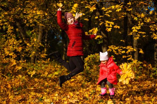 Young mother with her little daughter in an autumn park.