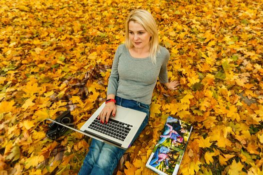 woman with laptop and photo book in autumn park.