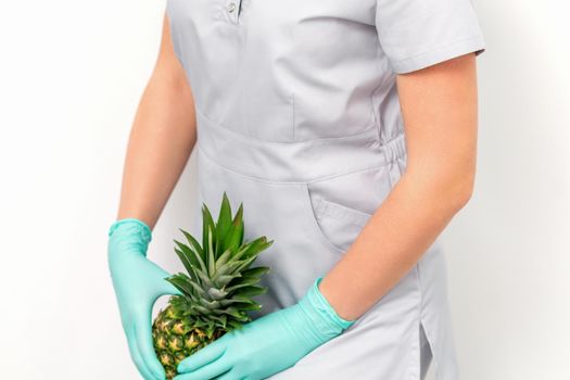 Female doctor beautician with pineapple. Concept of epilation or depilation and intimate hygiene