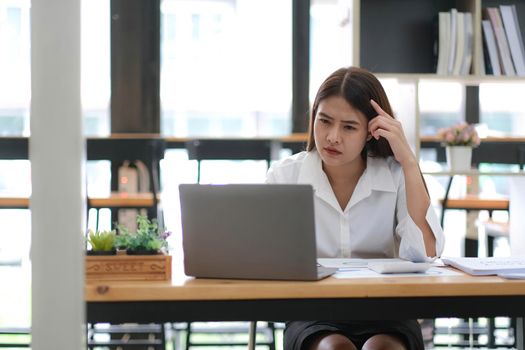 Image of an Asian woman who is tired and overthinking from working with a tablet at the office..