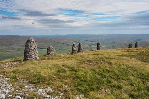 Multiple cairns standing tall at the summit of High White Scar, next to Wild Boar Fell, overlooking the Eden Valley, Cumbria, UK