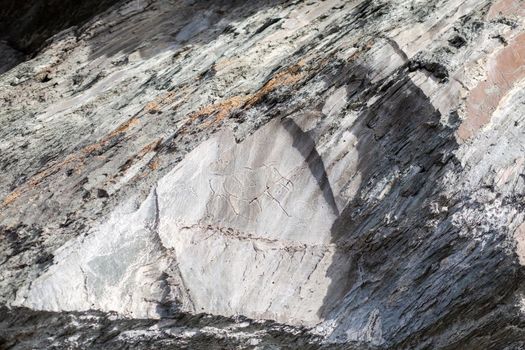 Old rock carvings of an ancient man on rocks in Siberia. The drawings depict animals and people