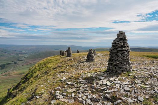 Multiple cairns standing tall at the summit of High White Scar, next to Wild Boar Fell, overlooking the Eden Valley, Cumbria, UK