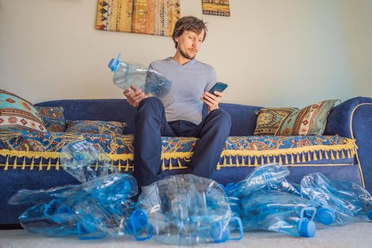 Young caucasian man hamong empty plastic bottles to recycle with sad expression.