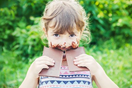 A sweet-toothed child eats chocolate. Selective focus.