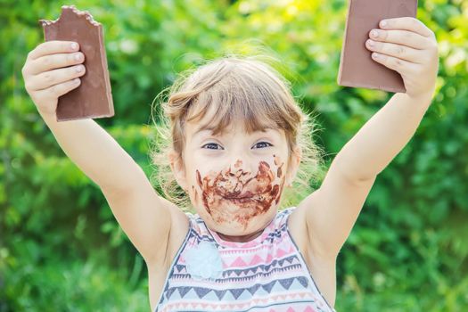 A sweet-toothed child eats chocolate. Selective focus.