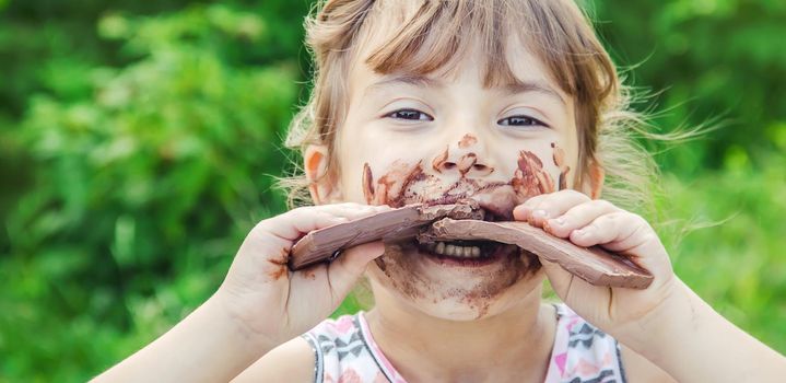 A sweet-toothed child eats chocolate. Selective focus.