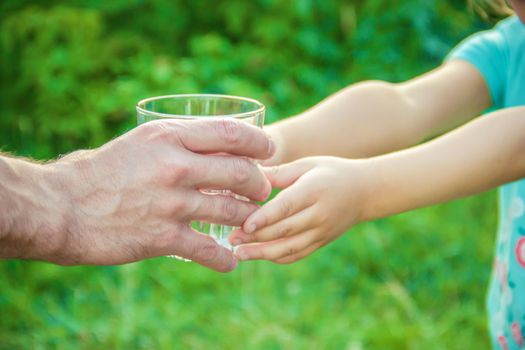 The father gives the child a glass of water. Selective focus.