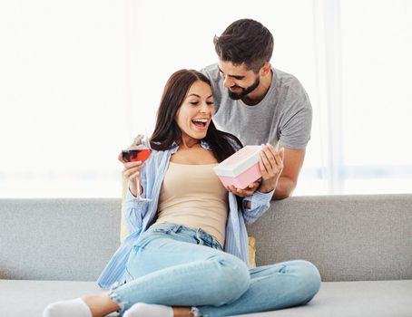 Smiling man surprises his girlfriend with present at home