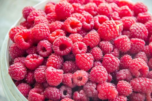 Raspberries are in the hands of a child in the form of a heart. nature.