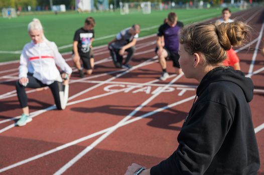 Female coach and group of children conducts a training session at the stadium. School gym trainings or athletics