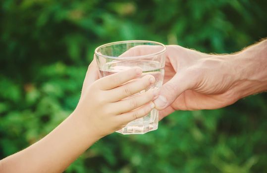 The father gives the child a glass of water. Selective focus.