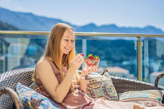 Portrait of gorgeous woman wearing beautiful dress sitting in a patio and eating strawberry.