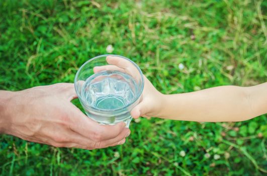 The father gives the child a glass of water. Selective focus.