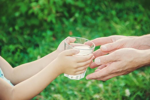 The father gives the child a glass of water. Selective focus.