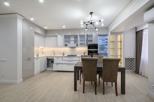 White modern new well designed white kitchen interior after renovation in studio apartment, windows covered with curtains