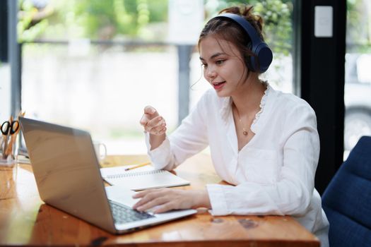Portrait of a beautiful woman using a computer and earphone during a video conference