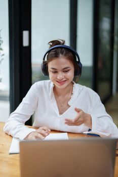 Portrait of a beautiful woman using a computer and earphone during a video conference