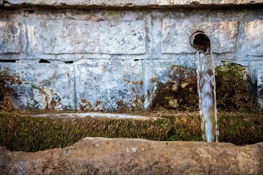 Old stone fountain with clear pure water running coming from a natural spring.
