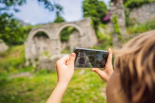 Augmented reality concept. Hand holding smart phone use AR application to check relevant information about building that was here in ancient times. Augmented reality in history and architecture.