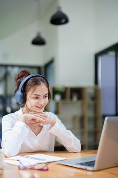 Portrait of a beautiful woman using a computer and earphone during a video conference