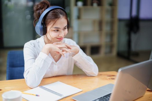 Portrait of a beautiful woman using a computer and earphone during a video conference