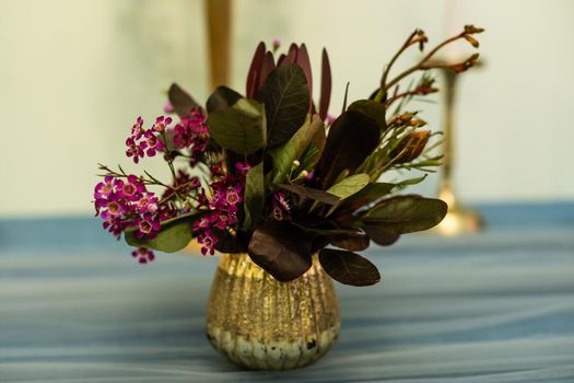 a purple flower in a golden vase.