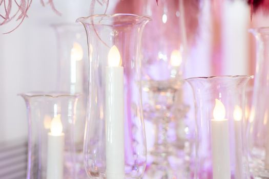 Burning candles in glasses on marble table.