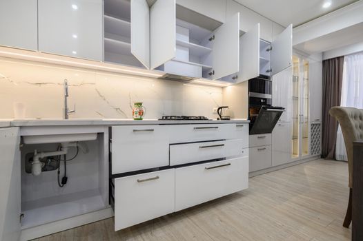 White modern new well designed white kitchen furniture in interior of studio apartment after renovation
