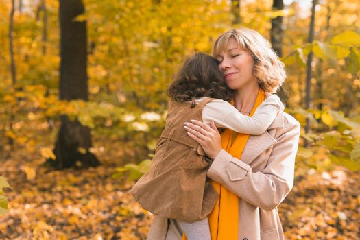 Mother with child in her arms against background of autumn nature. Family and season concept