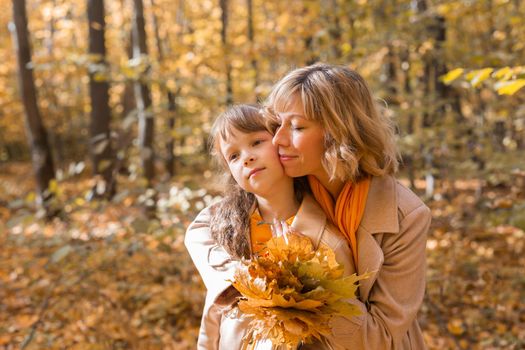 Beautiful lifestyle autumn photo mother and child walks evening in the park, warm sunlight