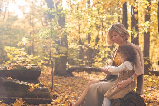 Beautiful lifestyle autumn photo mother and child walks evening in the park, warm sunlight
