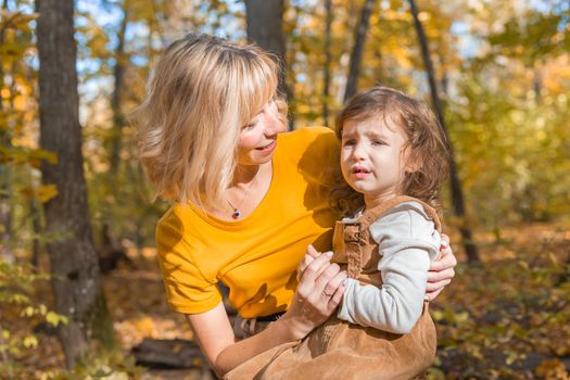 Beautiful lifestyle autumn photo mother and child walks evening in the park, warm sunlight
