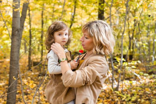 Beautiful lifestyle autumn photo mother and child walks evening in the park, warm sunlight