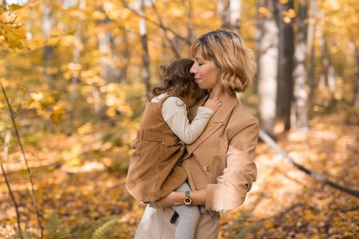 Beautiful lifestyle autumn photo mother and child walks evening in the park, warm sunlight