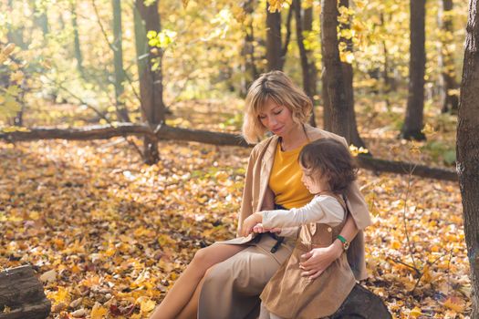 Beautiful lifestyle autumn photo mother and child walks evening in the park, warm sunlight
