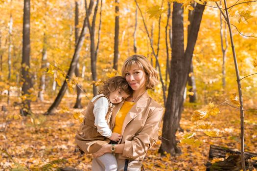 Beautiful lifestyle autumn photo mother and child walks evening in the park, warm sunlight