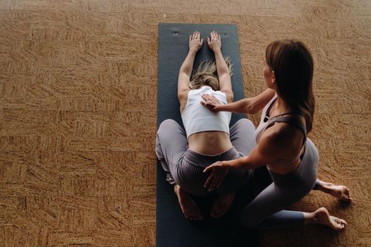 Yoga exercises. A personal trainer teaches a woman yoga classes in the gym.